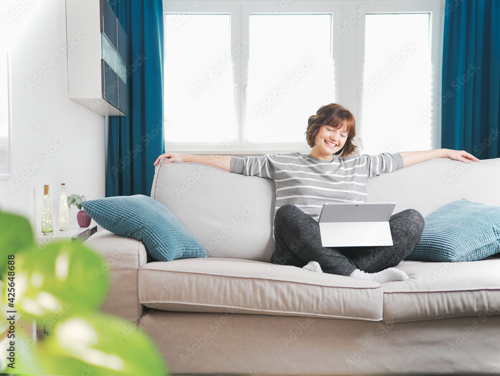 Smiling girl sit relax on couch using modern laptop.happy young woman freelance work on computer from home. social-distancing and self-isolation concept. coronavirus stay home and online live. Smiling girl sit relax on couch using modern laptop.happy young woman freelance work on computer from home. social-distancing and self-isolation concept. coronavirus stay home and online live.