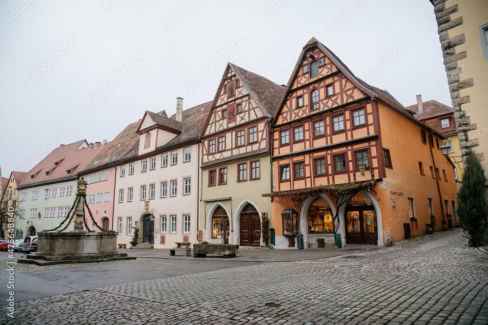 Medieval narrow street, colorful renaissance, gothic historical buildings, Stone fountain Herrnbrunnen, half-timbered house, old town, Rothenburg ob der Tauber, Bavaria, Germany