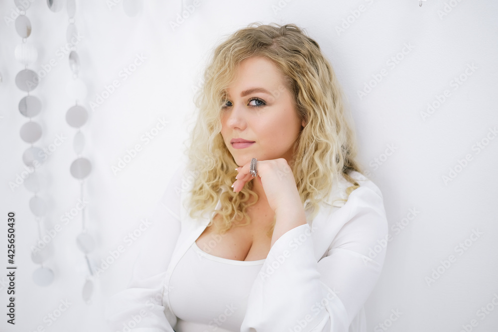 Young blond woman model xl plussize sitting on the floor and looking at the camera on white background Young blond woman model xl plussize sitting on the floor and looking at the camera on white background
