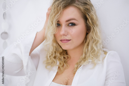 Young blond woman model xl plussize sitting on the floor and looking at the camera on white background