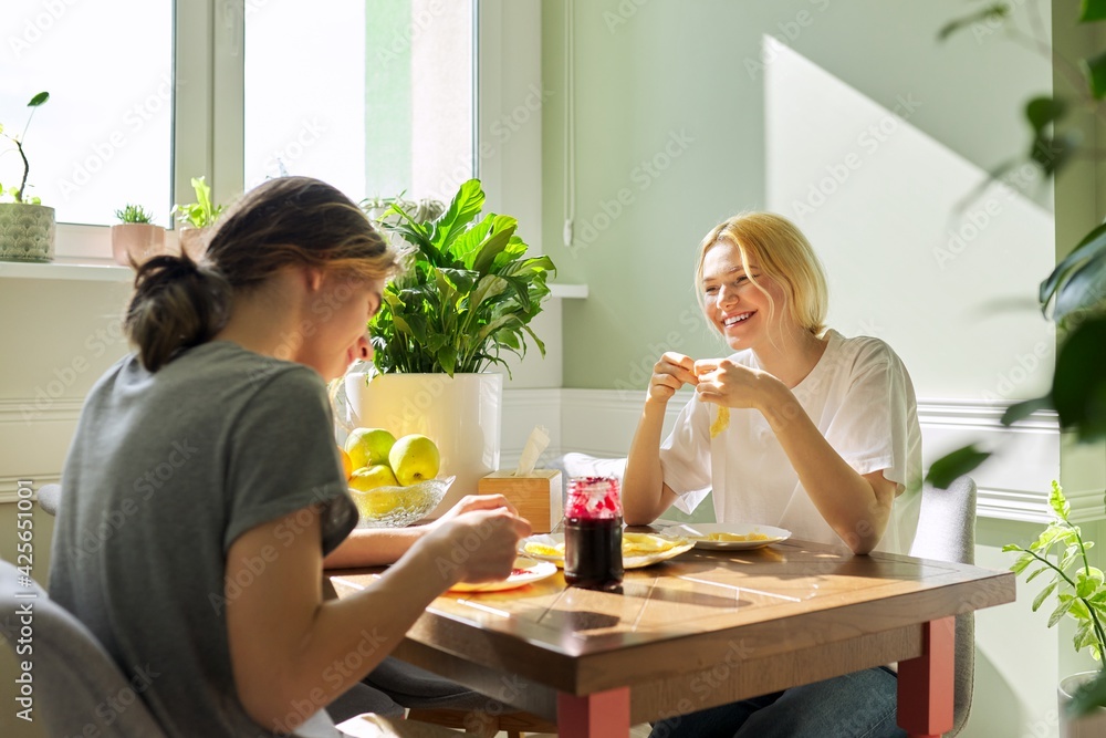 Teenagers guy and girl eating pancakes with jam, sitting at table at home Teenagers guy and girl eating pancakes with jam, sitting at table at home