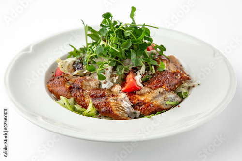 Salad of smoked eel, unagi sauce and greens with vegetables. Banquet festive dishes. Gourmet restaurant menu. White background.