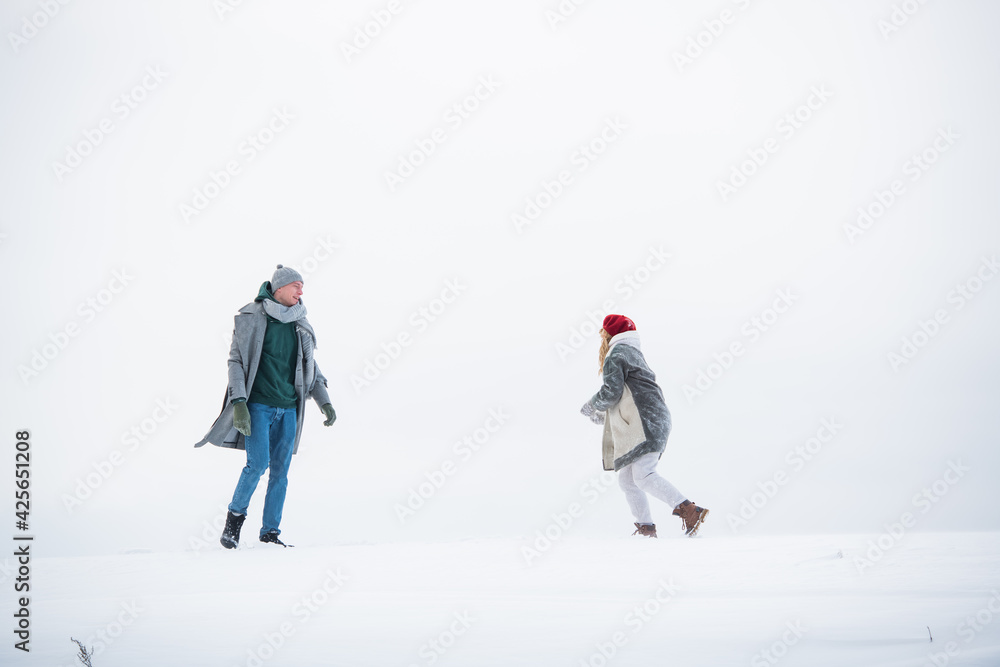 On a white background of a snowy plain, a couple of lovers run and hug during a date On a white background of a snowy plain, a couple of lovers run and hug during a date