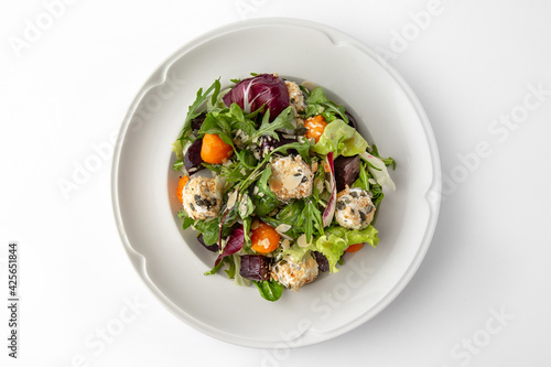 Vegetarian salad with balls of tofu and nuts, roasted beets, carrots and greens. Banquet festive dishes. Gourmet restaurant menu. White background.