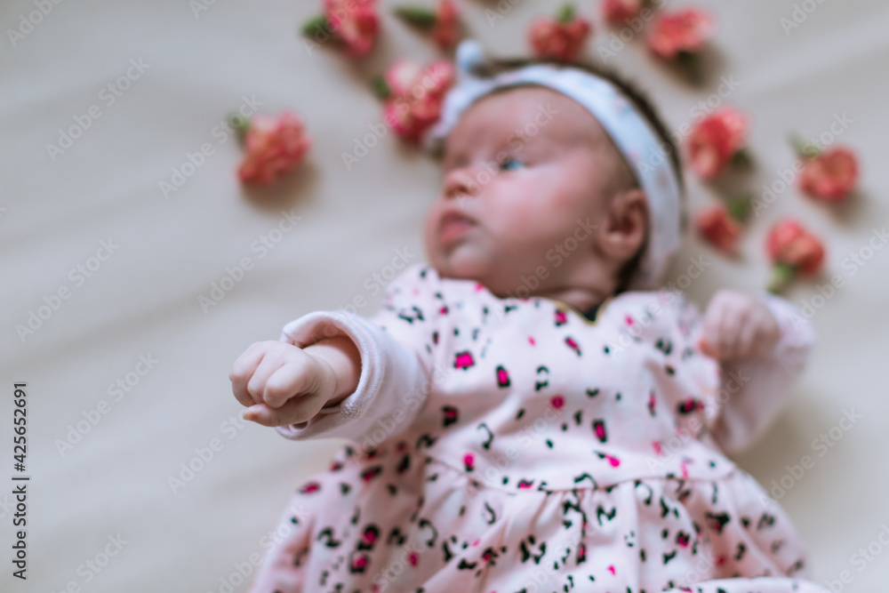 Toddler girl. Newborn. Lying down. Emotions. Top view. Scattered flowers. Toddler girl. Newborn. Lying down. Emotions. Top view. Scattered flowers.