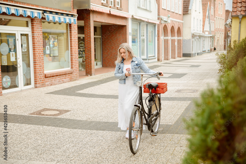 Sympathetic woman walks in the city center with her bike. Bicycle rails in the pedestrian zone. European city. Spring mood