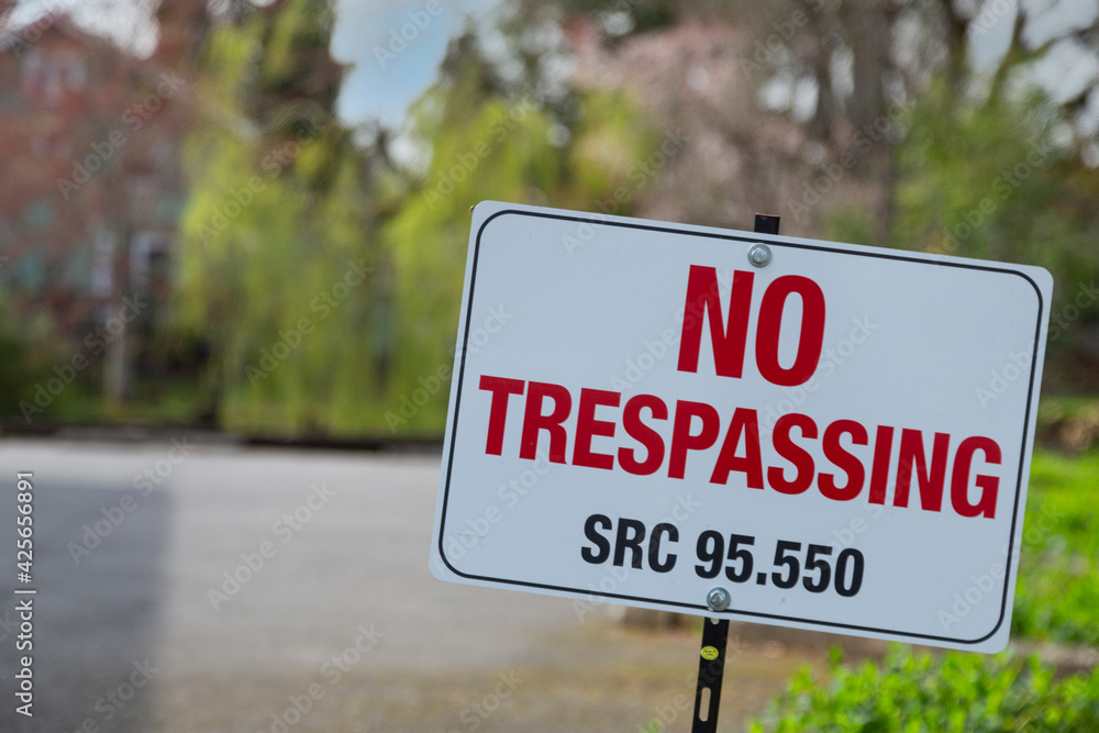 No trespassing sign, quoting SRC code 95.550, on a spike with an out of focus background No trespassing sign, quoting SRC code 95.550, on a spike with an out of focus background