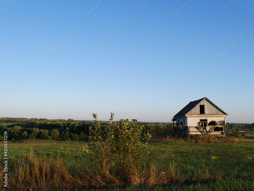 A lonely ruined house standing on a hill. Summer and lots of green grass. Space for text
