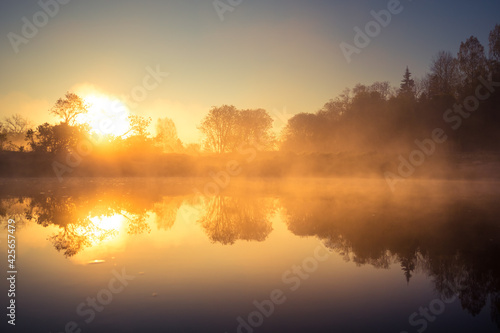 A beautiful river morning with mist and sun light. Springtime scenery of river banks in Northern Europe. Warm  colorful look.