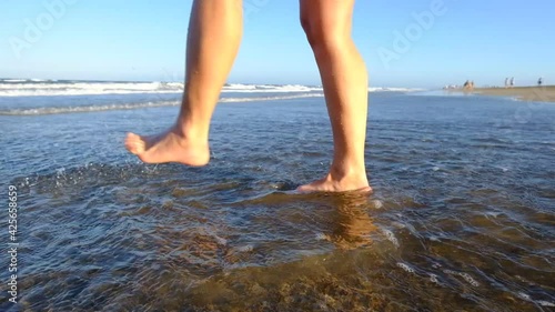 Feet moving on the shore of the beach with the sea water