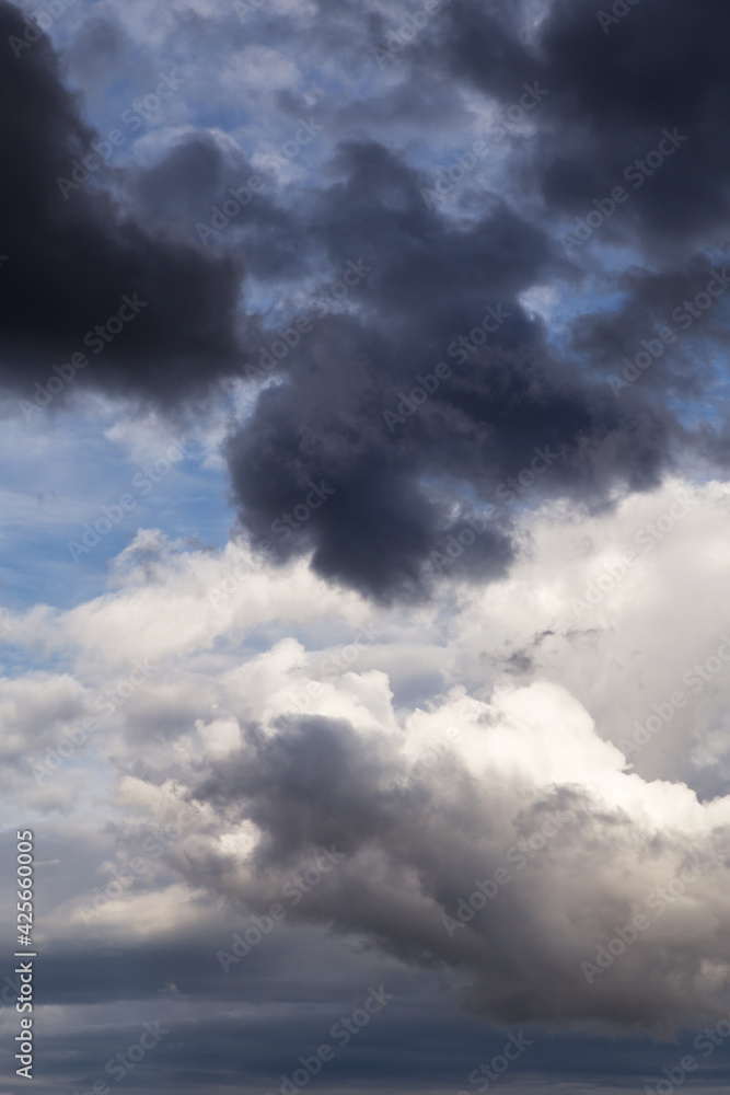 Fototapeta premium Thunderstorm clouds texture. Storm sky with dark grey and white cumulus clouds against blue sky background
