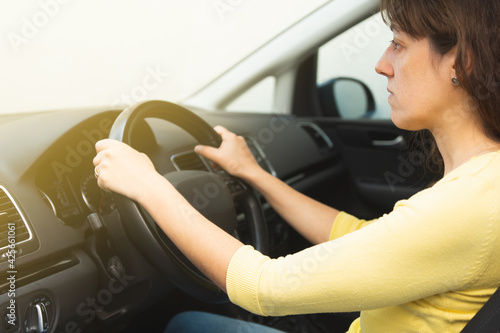 concentrated young woman driving a car wearing yellow sweater