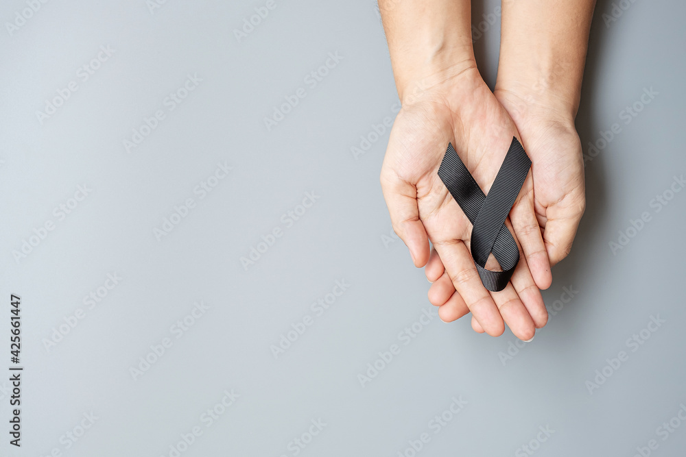 Fototapeta premium Melanoma and skin cancer, Vaccine injury awareness month and rest in peace concepts. Man holding black Ribbon on grey background