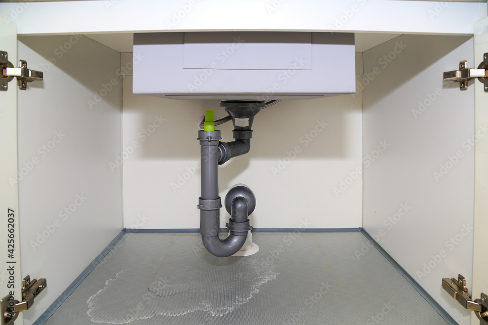 Water leaks from the drain hose under the sink. Stock Photo Adobe Stock