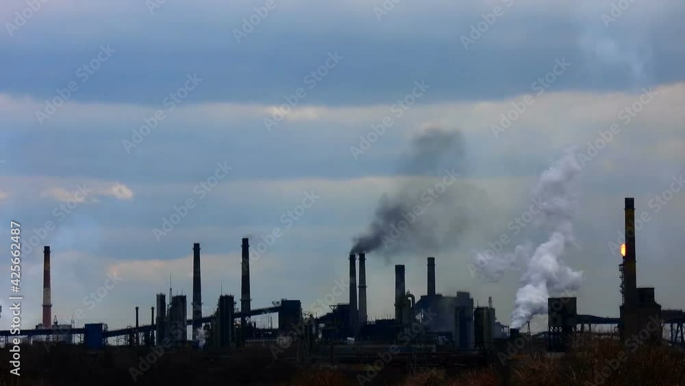 Air pollution from an industrial factory. Dirty blue sky. Metallurgical factory. Industrial landscape. Silhouettes of the plant. Global warming concept. Iron ore processing. Air pollution from an industrial factory. Dirty blue sky. Metallurgical factory. Industrial landscape. Silhouettes of the plant. Global warming concept. Iron ore processing.