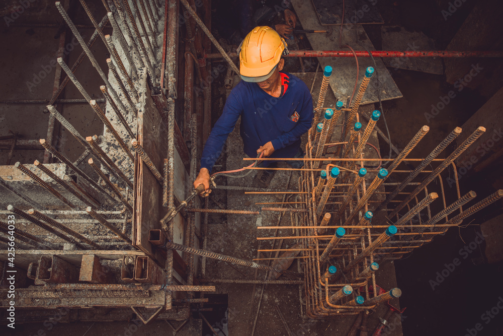 Construction Worker Undoing Formwork Studs In Basement Concrete Wall