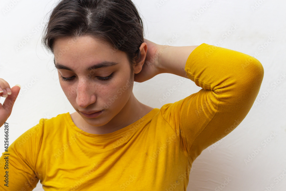 Woman in yellow t-shirt on white background tying hair Woman in yellow t-shirt on white background tying hair