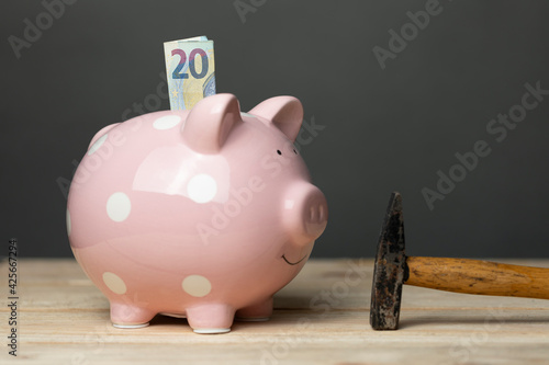 rosa Sparschwein mit 20 Euro Geldschein und Hammer auf Holztisch - pink saving pig with 20 Euro and one hammer on a Woodplate photo