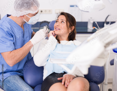Dentist talking to female patient complaining of toothache at dentist office