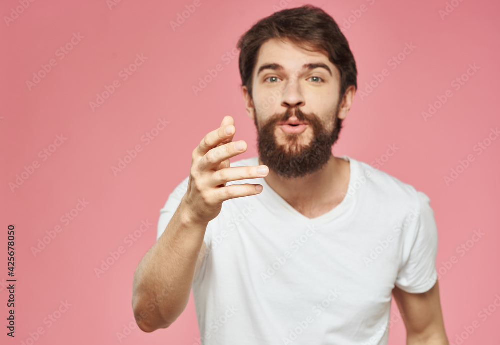 Fototapeta premium An energetic man on a pink background gestures with his hands
