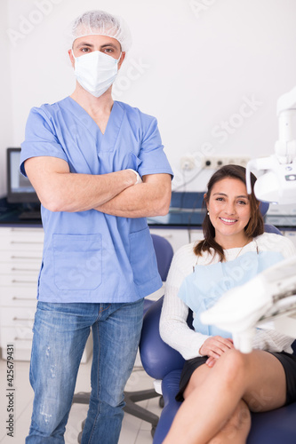 Smiling satisfied latin american woman visiting dentist in dental office