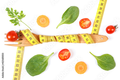 Wooden fork wrapped in tape measure and fresh ripe vegetables  concept of slimming