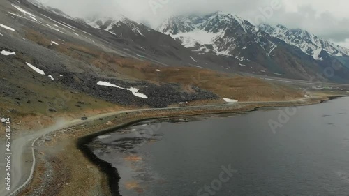 Aerial View Of SUV Driving On Gravel Road Beside Shandur Lake In Pakistan. Dolly Forward photo