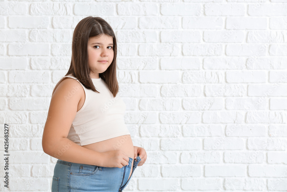 Foto Stock Overweight girl in tight clothes on white brick background |  Adobe Stock