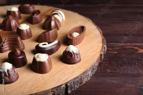 Board with tasty chocolate candies on wooden background