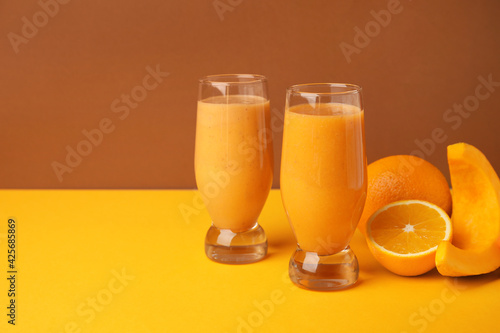Glasses of healthy smoothie and ingredients on color background