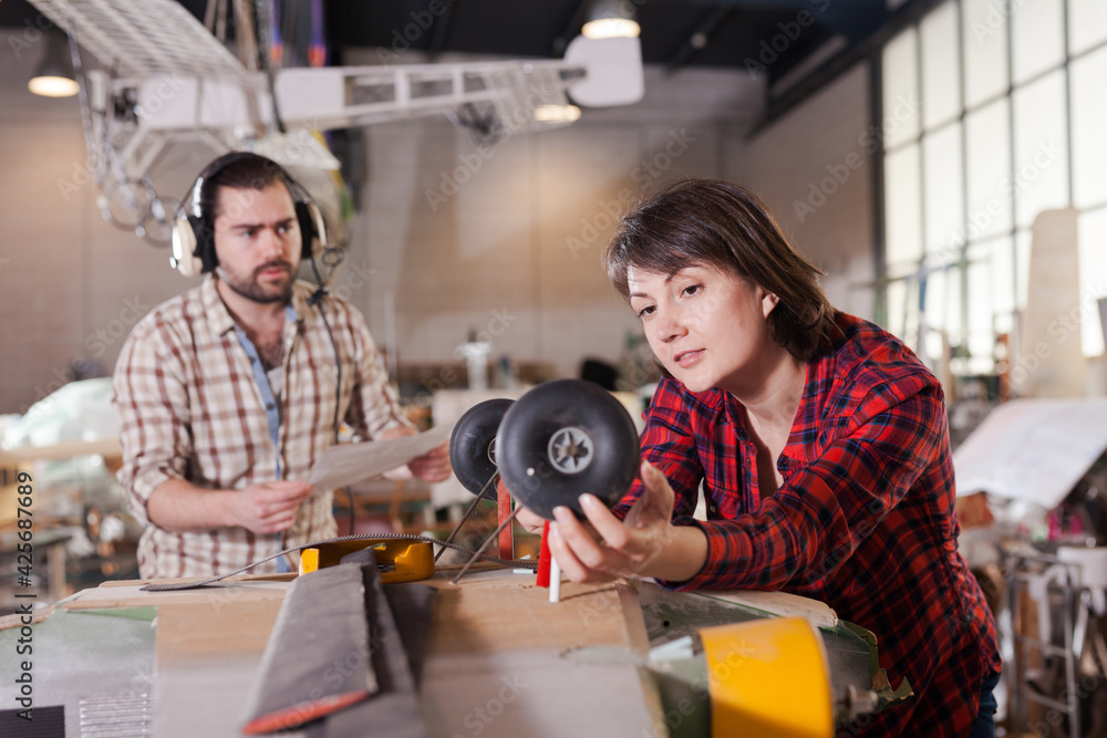 Obraz premium Female aircraft enthusiast engaged in creating plane models in workshop..