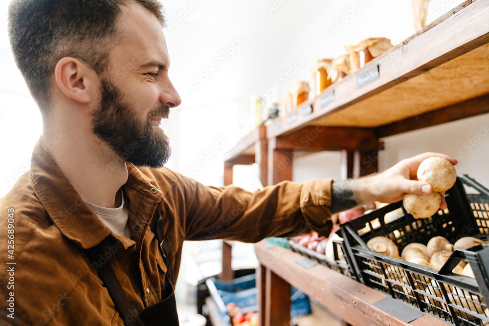 White bearded seller man smiling while working in local eco shop White bearded seller man smiling while working in local eco shop