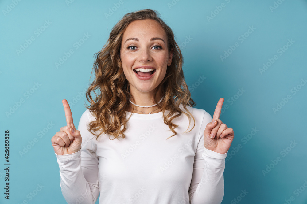 Blonde young woman smiling and pointing finger upward Blonde young woman smiling and pointing finger upward