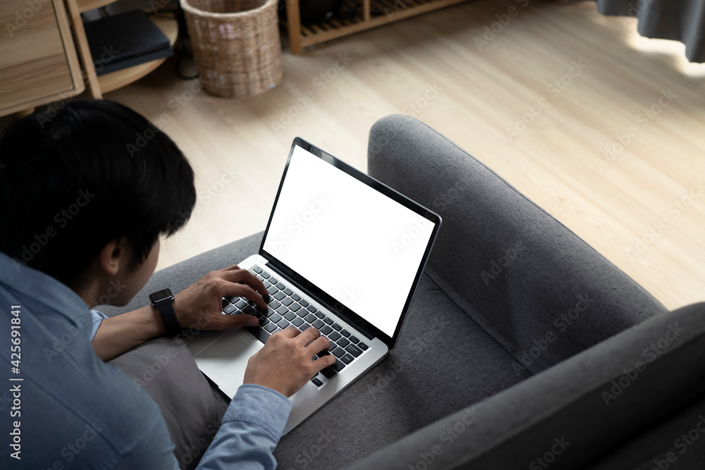 Young asian man lying on sofa and surfing internet with laptop computer. Young asian man lying on sofa and surfing internet with laptop computer.