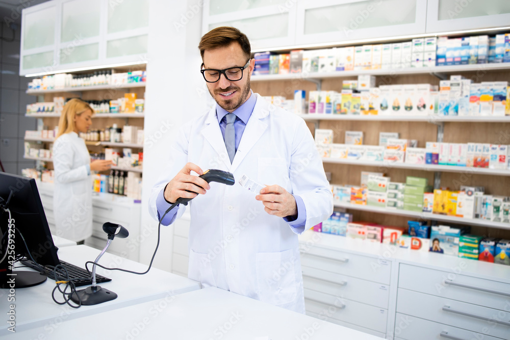 Pharmacist holding bar code reader in pharmacy store and selling medicines.