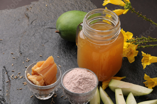 Raw Mango juice - Aam Panna or Panha in a transparent glass with whole green fruit, photo