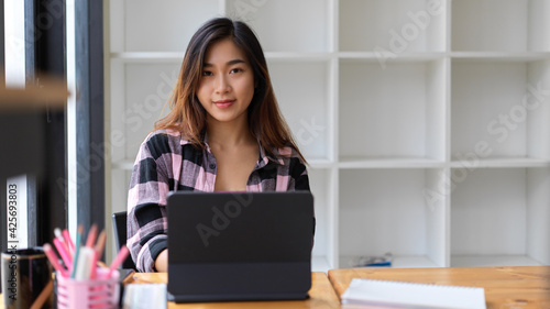 Portrait of female student looking into camera while doing assignment in library