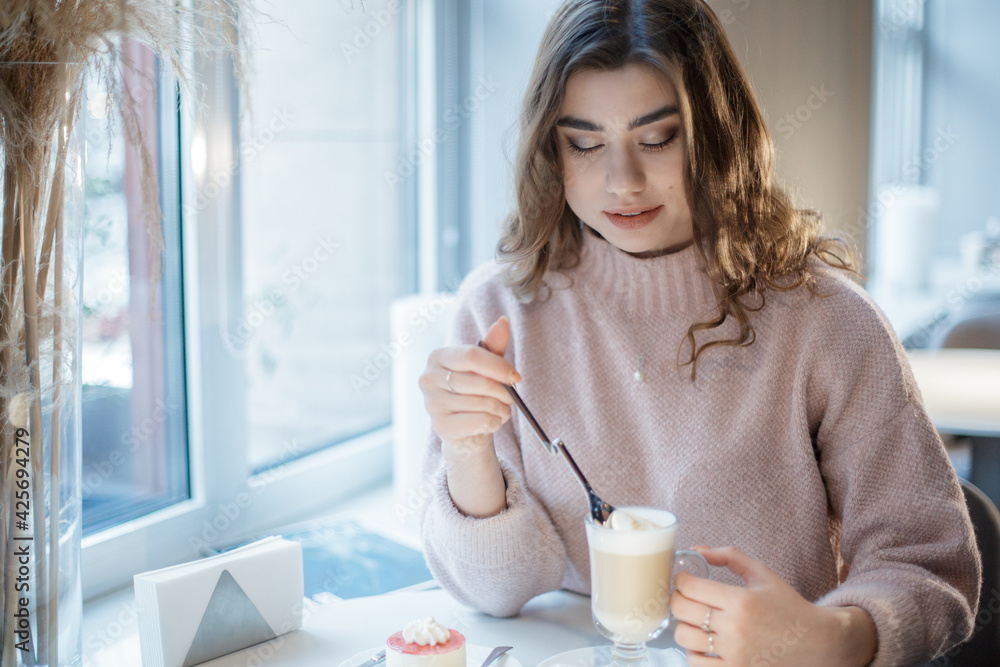 Pretty young woman sitting in the cafe with a cup of cappuccino. Pretty young woman sitting in the cafe with a cup of cappuccino.