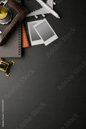 Dark creative flat lay workspace with camera, photo card frame, notebook, travel items and copy space