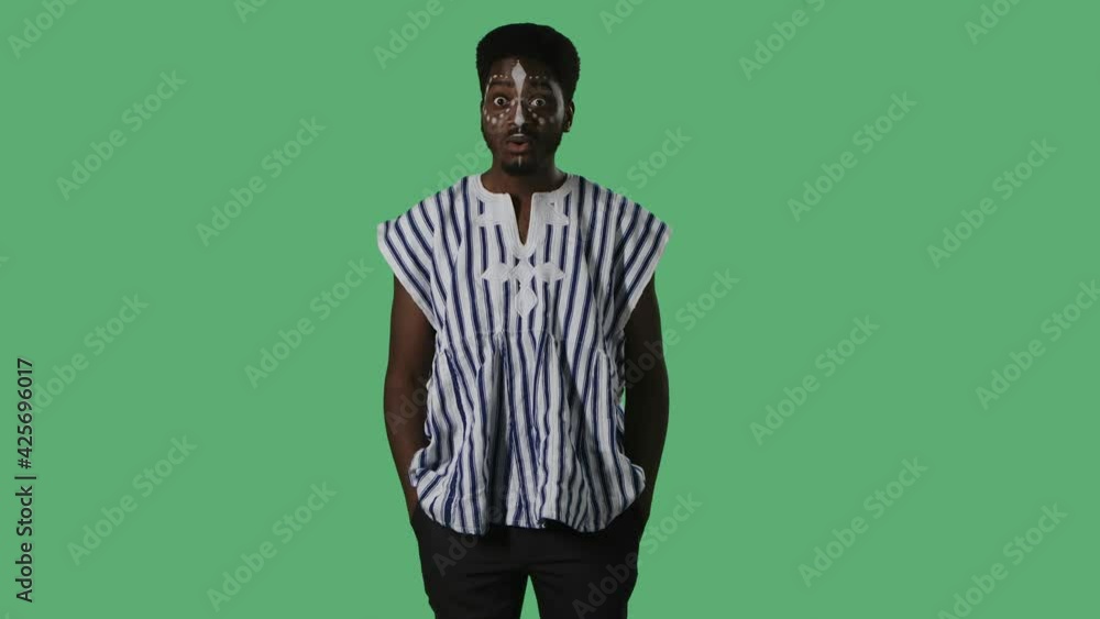Portrait young African American man with a wow shocked and surprised expression. Black male with an ethnic white pattern on face and in striped national shirt posing on green screen in studio. Portrait young African American man with a wow shocked and surprised expression. Black male with an ethnic white pattern on face and in striped national shirt posing on green screen in studio.