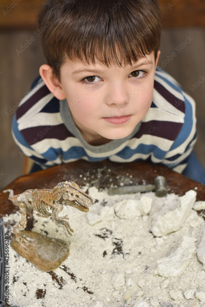 Happy child digging the dinosaur and having fun with archaeology