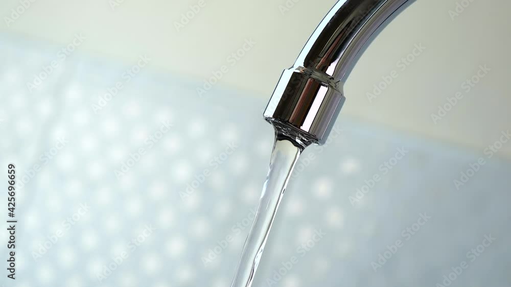 Slow motion of turn off faucet and water flowing stop from a sink in the kitchen Slow motion of turn off faucet and water flowing stop from a sink in the kitchen
