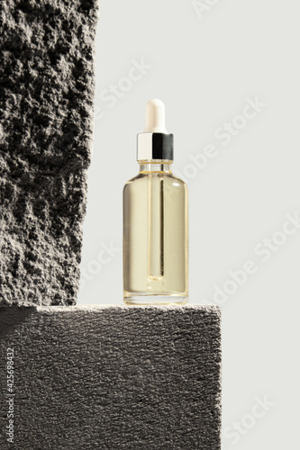 Dropper glass with skincare oil Bottle Mock-Up. Сosmetic pipette on concrete background.