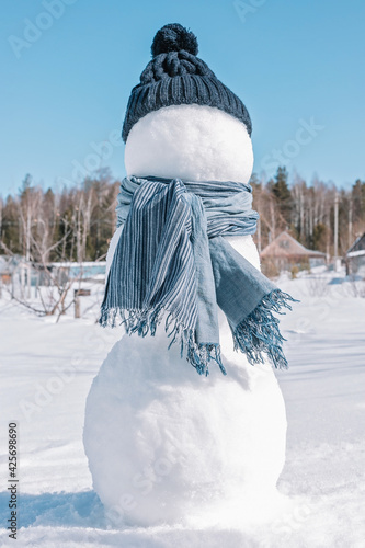 Fotografía A snowman in a blue hat and scarf is standing in the field