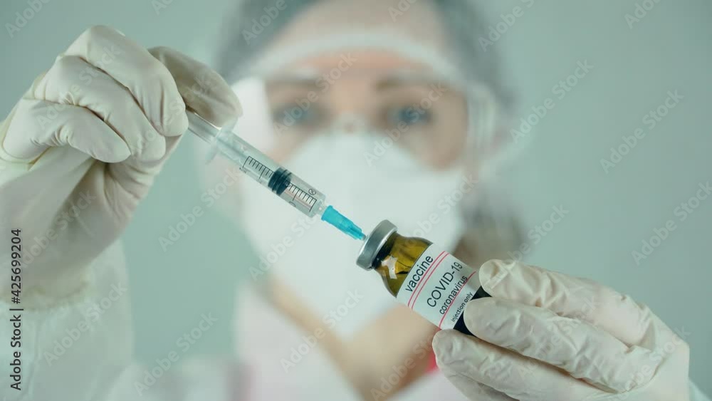 Medical doctor filling syringe from vial with anti coronavirus vaccine or medication in laboratory. Medicines research concept and defeating dangerous covid-19 infection Medical doctor filling syringe from vial with anti coronavirus vaccine or medication in laboratory. Medicines research concept and defeating dangerous covid-19 infection