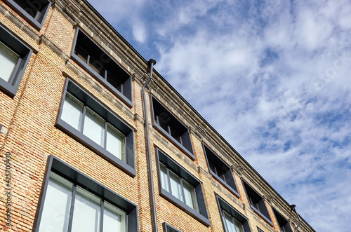 Brick building with windows and downspout against blue sky