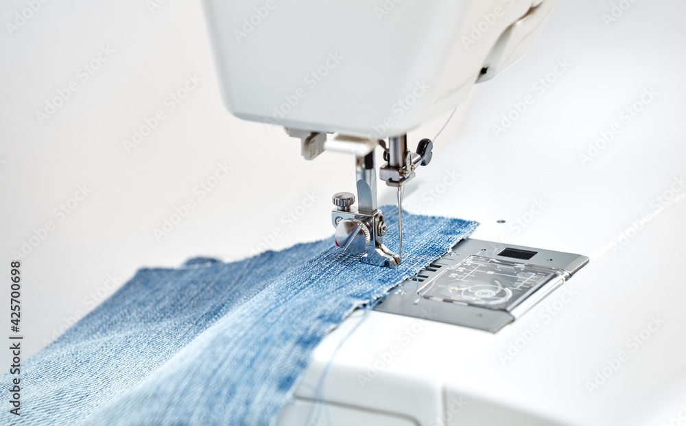 Sewing machine working part with blue denim cloth, replacement foot. A close-up shows a needle passing through tissue