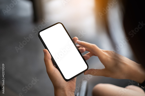 Close up of hand holding, using cell phone with blank screen in coffee shop after covid-19 have vaccine.