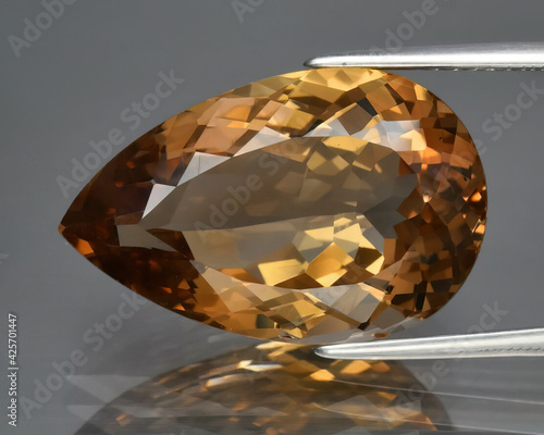 Fotografi Natural gemstone orange imperial topaz on gray background