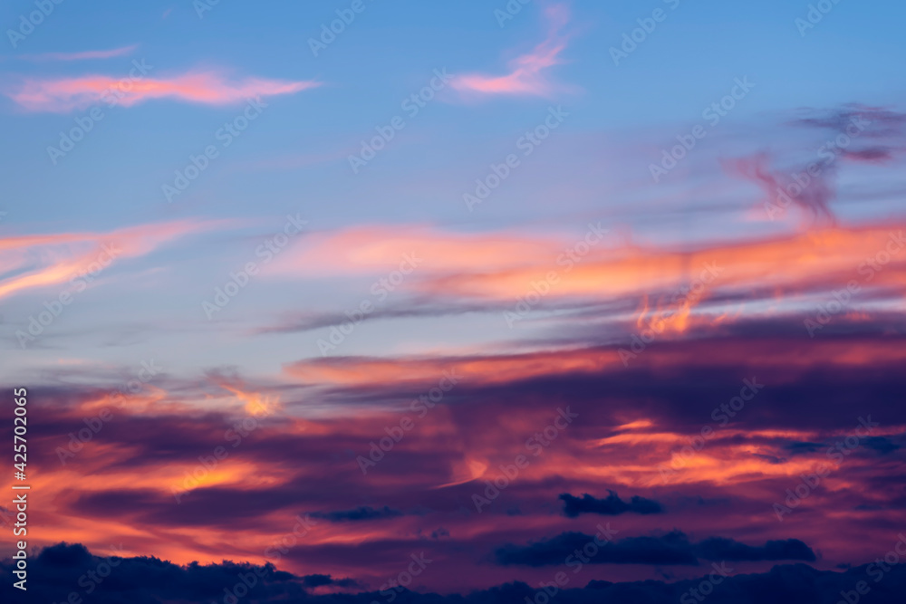 A colorful sky at sunset with clouds painted in many shades from pink to black